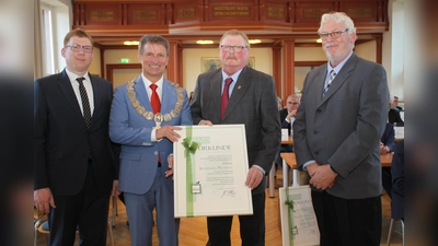 Im Beisein von Hohenwepels Ortvorsteher Daniel Strathaus (links) und Alttraktorenclub-Vorstand Godehard Bierhoff (rechts) nimmt Johannes Reineke von Landrat Michael Stickeln die Auszeichnung entgegen. (Foto: Kreis Höxter)