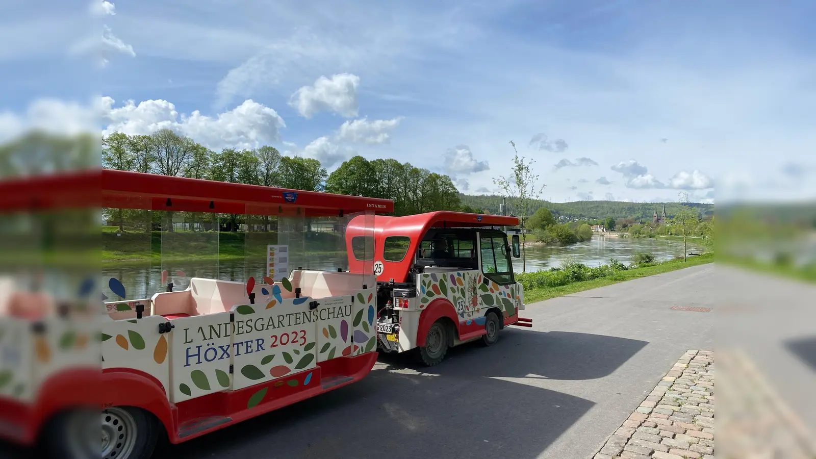 Entlang der Flusspromenade: Die Höxter Bimmelbahn bei ihrer Fahrt auf dem Weserradweg. Sie pendelt zwischen der Altstadt und dem Archäologiepark nahe Schloss Corvey.  (Foto: Huxarium Gartenpark Höxter gGmbH)