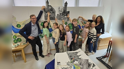 Die Schülerinnen und Schüler der 4. Jahrgangsstufe der Graf-Dodiko-Grundschule platzieren unter der Leitung von (von rechts) Anne Schäfers und Katrin Filker die charakteristischen Merkmale von Warburgs Ortschaften auf der Außenwand des Festwagens. Bürgermeister Tobias Scherf (links) zeigt sich begeistert von der kreativen Umsetzung des Mottos der „50 Jahre eine Stadt – Warburg und seine Dörfer“. (Foto: Stadt Warburg)