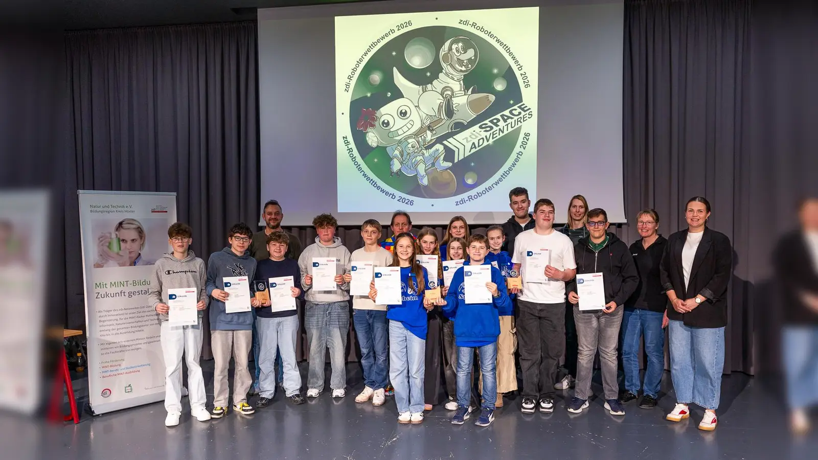 Strahlende Gesichter beim zdi-Roboterwettbewerb in Steinheim (v.l.): Schülerinnen und Schüler der drei Gewinnerteams „Code-Attack“ (Realschule / Gymnasium, Steinheim), „Chefköche“ (Erd-Charta-Schule, städtische Sekundarschule Warburg mit Teilstandort Borgentreich), „Xaverianer“ (Gymnasium St. Xaver, Bad Driburg) Schiedsrichterin Jenny Kociemba sowie Juliane Jütten (Geschäftsstelle Verein Natur und Technik / zdi-Netzwerkkoordinatorin). (Foto: Natur und Technik e.V.)