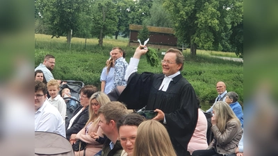 Pfarrer Gunnar Wirth erinnert die Taufgottesdienstbesuchenden mit versprengten Wassertropfen an ihre eigene Taufe.  (Foto: Barbara Siebrecht)