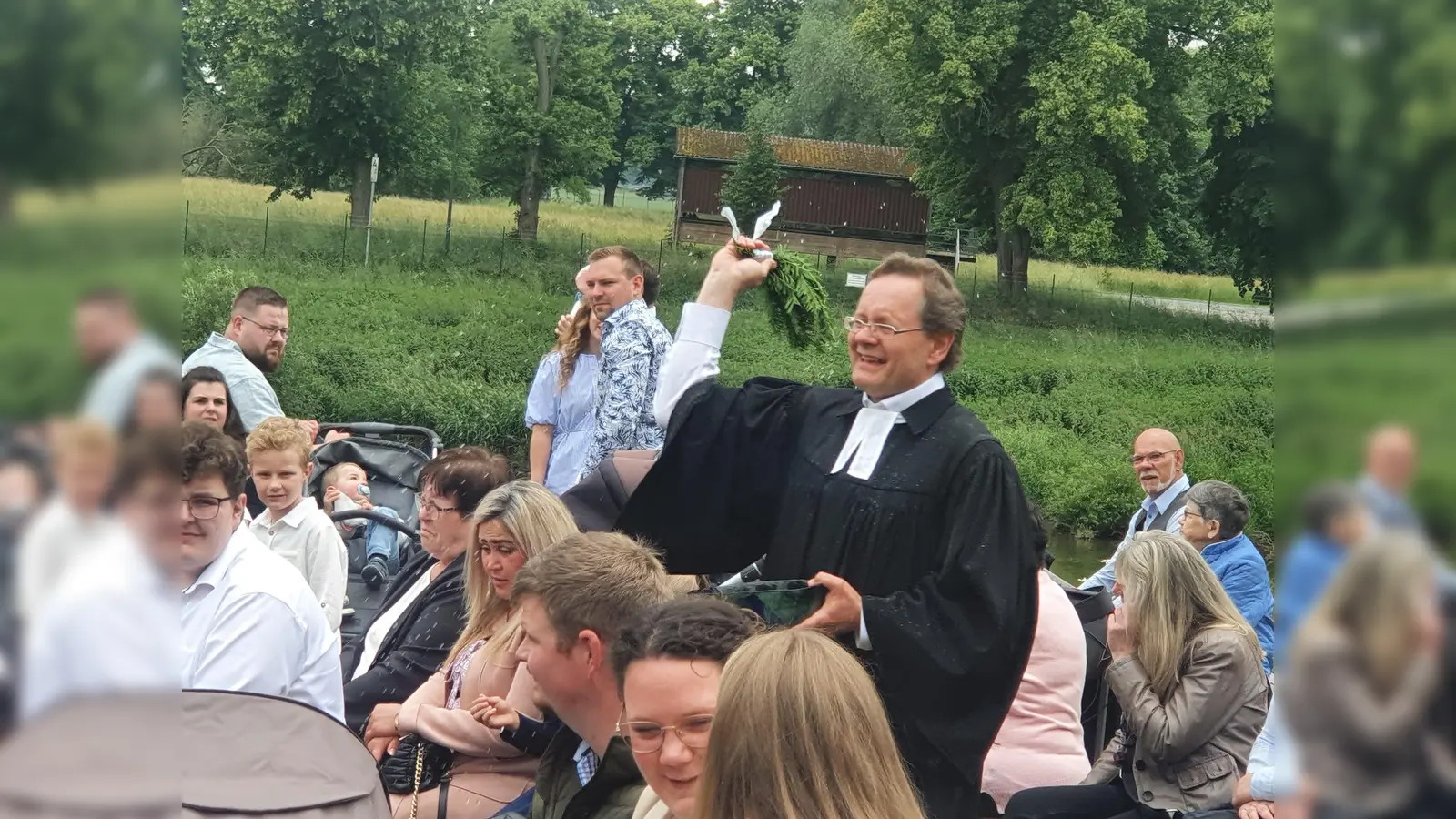 Pfarrer Gunnar Wirth erinnert die Taufgottesdienstbesuchenden mit versprengten Wassertropfen an ihre eigene Taufe.  (Foto: Barbara Siebrecht)