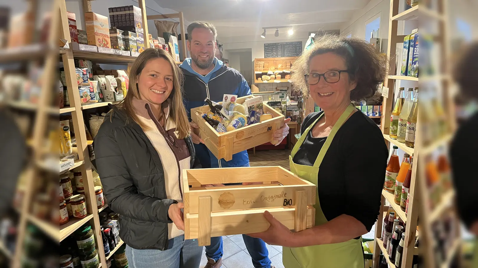 Gemeinsam haben Laura Jäger (l.), Öko-Modellmanagerin des Kreises Höxter, und Heiko Böddeker von der Regionalmarke Kulturland bei der GfW Höxter die leeren Holz-Biokisten an regionale Bio-Betriebe in der Region übergeben. In Körbecke freute sich Heike Schäfer-Jacobi (r.) vom Biohof Jacobi darüber. Auch in ihrem Hofladen steht die Kiste mit regionalen Bio-Spezialitäten zukünftig bereit. (Foto: Kreis Höxter)