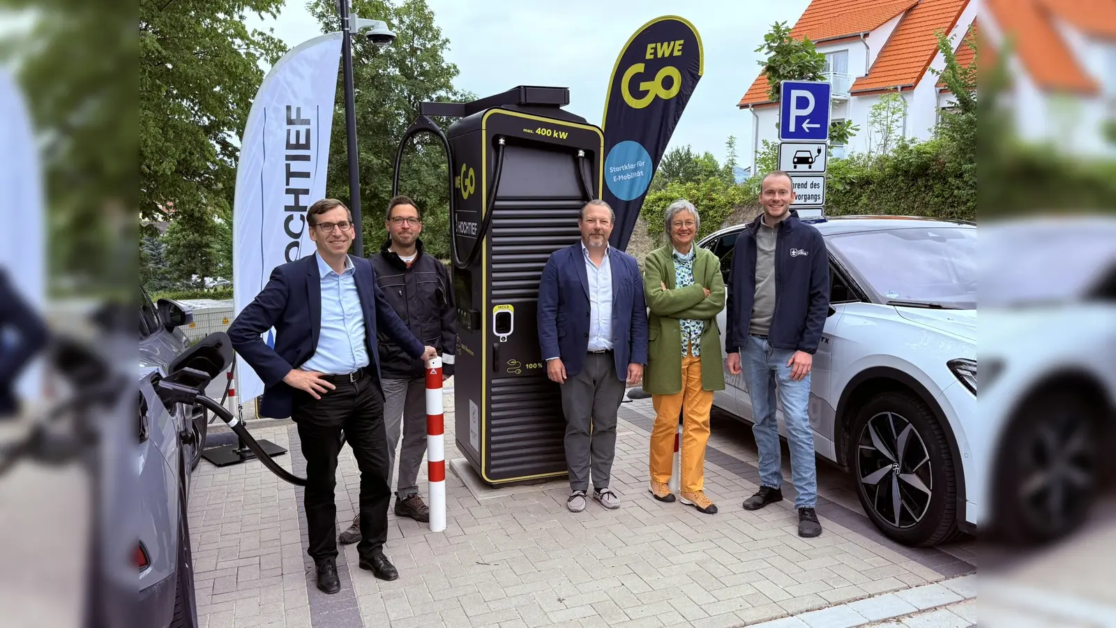 Bürgermeister Tobias Scherf (von links), der Mobilitätsbeauftragte Jan Kolditz, Simon Stein (Geschäftsführer EWE Go HOCHTIEF Ladepartner GmbH &amp; Co. KG), die Mobilitätsausschuss-Vorsitzende Doris Hauck und der Touristiker Lucas Simon zwischen zwei Ladeplätzen, auf denen zukünftig E-Autos mit einer Leistung von bis zu 400 kW pro Ladestation geladen werden können. (Foto: EWE Go)