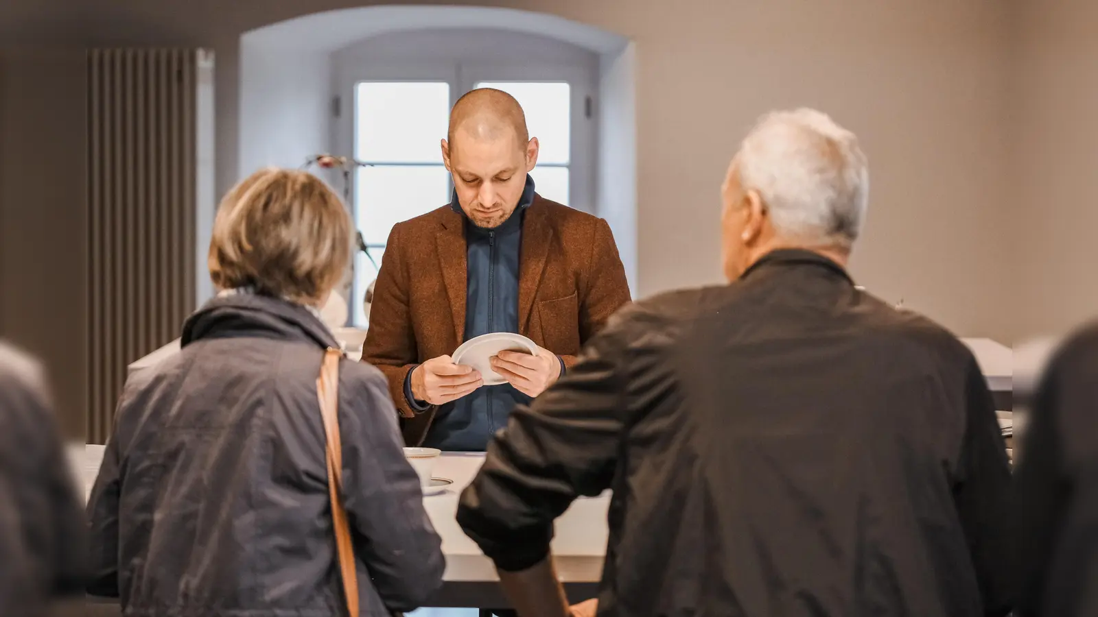 Der Museumsleiter begutachtet porzelanene Schätze der Gäste.  (Foto: Claudia Warneke)