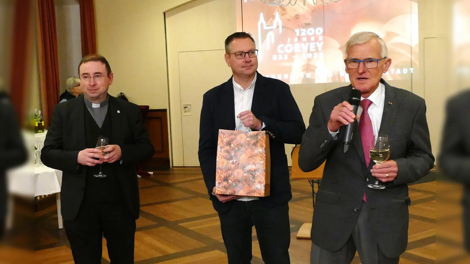 Dem Pfarrdechanten Dr. Hans-Bernd Krismanek (links) dankte Kirchenvorstand Josef Kowalski (rechts) für seine kooperative, persönlich zugewandte und alle Projekt-Beteiligten einbindende Führung. Zusammen mit Marcus Beverungen, Verwaltungsleiter des Pastoralverbundes Corvey, überreichte er dem Geistlichen als Zeichen der Wertschätzung ein Präsent.  (Foto: Kirchengemeinde Corvey)