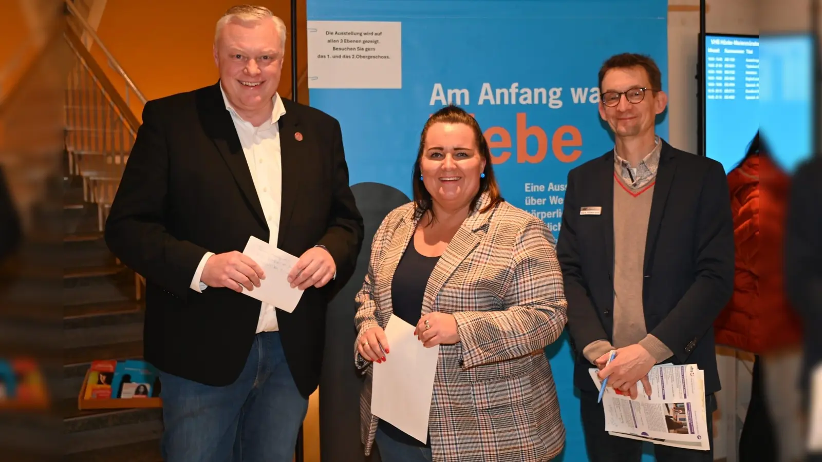 VHS-Leiter Hildebrand, Gleichstellungsbeauftragte Nadine Nolte und Bürgermeister Hartmann eröffnen gemeinsam die Ausstellung „Am Anfang war es Liebe…“ im Foyer der Volkshochschule Höxter. (Foto: Thomas Kube)