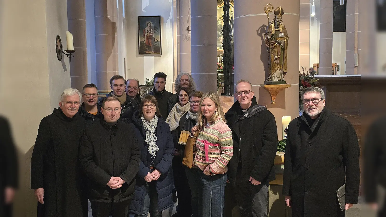In der Nikolaikirche in Höxters Innenstadt bauen das Vitus-Gemälde im Hintergrund und auch die Statue des Corveyer Schutzpatrons am Hochalter Brücken zur ehemaligen Benediktinerabtei. Im Bild (von links) Pater Werner Vullhorst, Marcus Beverungen, Pfarrdechant Dr. Hans-Bernd Krismanek, Marco Lämmchen, Hans-Hermann Jansen, Nicole Raabe, Carsten Sperling, Dr. Holger Kempkens, Annika Winkler, Annika Pröbe, Margit Streicher-Bönnighausen, Dr. Peter Jochem und Pfarrer Günter Eickelmann. (Foto: Kirchengemeinde Corvey)