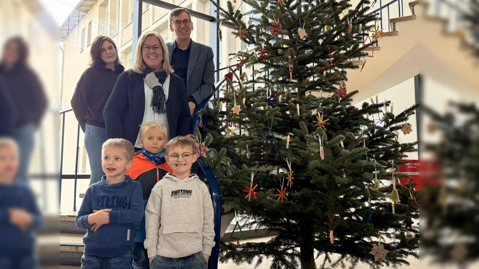 Bürgermeister Tobias Scherf freut sich über den festlich geschmückten Baum, den die Kinder der Adolph-Kolping-Kita in Welda gemeinsam mit Lena Kowalke (oben links, stellv. Kita-Leitung) und Mareike Huschen (oben Mitte, Kita-Leitung) mit ihrem selbst gebastelten Baumschmuck verziert haben. (Foto: Stadt Warburg)