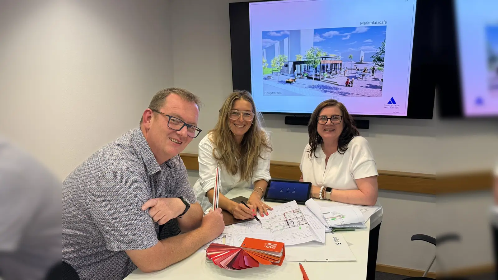 Mit den Bauplänen für das neue Marktplatzcafé: (von links) Christoph Bassani (Bassani und Partner), Claudia Ronge (helle freude.innenarchitekten) und Sonja Micus (Bassani und Partner). (Foto: Stadt Warburg)
