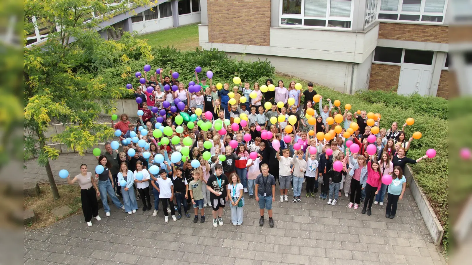 Die Schülerinnen und Schüler des neuen Jahrgangs 5 mit ihren Klassenleitungen am Kennenlern-Nachmittag im Juli 2025. Die Luftballons galten als Erkennungszeichen für die Klassen 5a bis 5f. (Foto: GEB)
