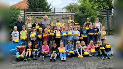 Die zweiten Klassen der Graf-Dodiko-Schule in Warburg zeigten stolz ihre neuen gelben Bio-Brotboxen. Günter Schumacher (Bürgerinitiative), Josef Jacobi (BI/Biohof Jacobi) und Julia Engemann (Biolandhof Engemann) hatten sie den Kindern überreicht. Hintere Reihe (v.l.): Günter Schumacher, Klassenlehrerin Elke Becker-Lenz, Julia Engemann, Josef Jacobi, Schulleiterin Christina Jakobi und Klassenlehrerin Ines Heinisch. (Foto: BI Lebenswertes Bördeland und Diemeltal)