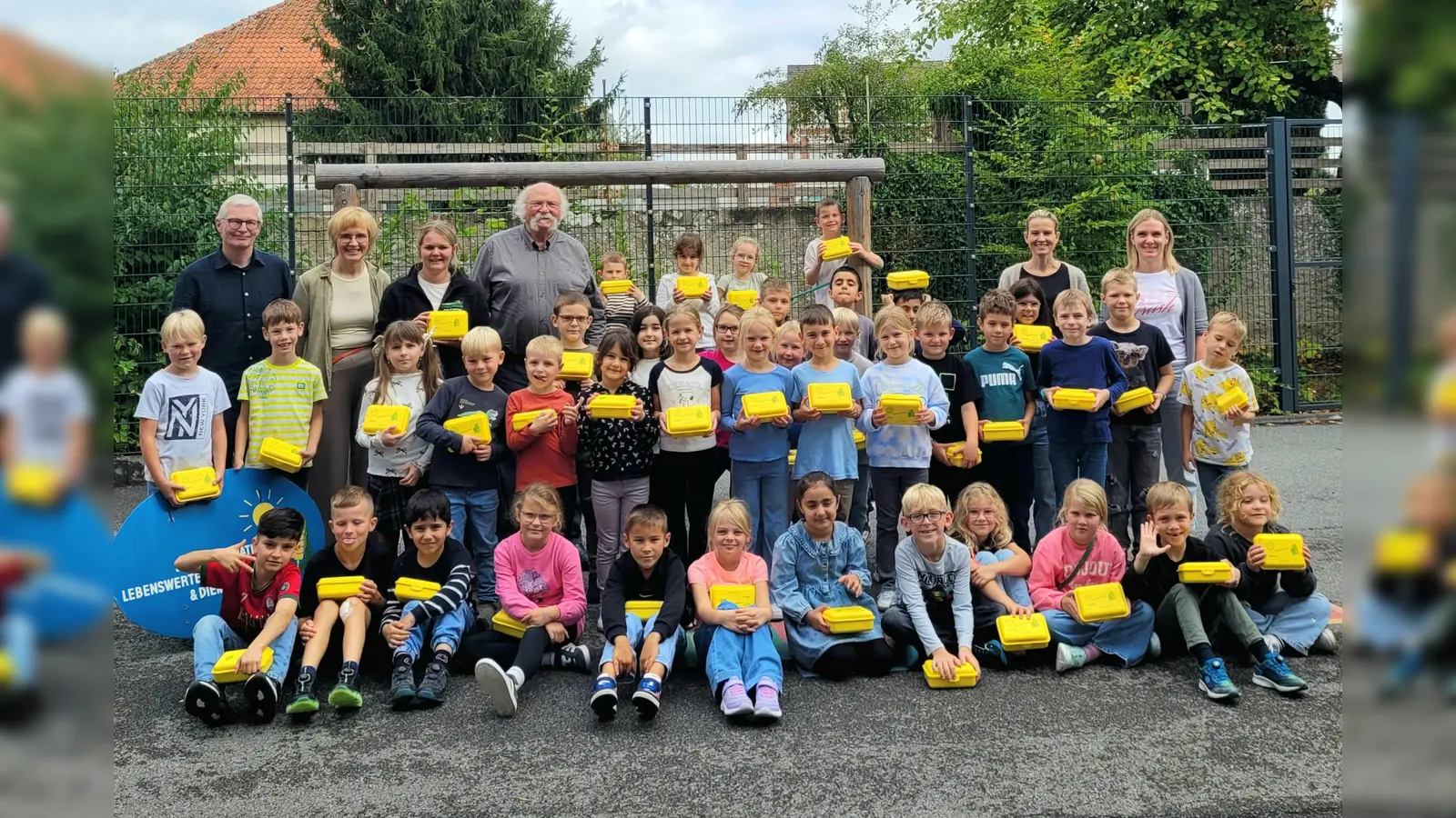Die zweiten Klassen der Graf-Dodiko-Schule in Warburg zeigten stolz ihre neuen gelben Bio-Brotboxen. Günter Schumacher (Bürgerinitiative), Josef Jacobi (BI/Biohof Jacobi) und Julia Engemann (Biolandhof Engemann) hatten sie den Kindern überreicht. Hintere Reihe (v.l.): Günter Schumacher, Klassenlehrerin Elke Becker-Lenz, Julia Engemann, Josef Jacobi, Schulleiterin Christina Jakobi und Klassenlehrerin Ines Heinisch. (Foto: BI Lebenswertes Bördeland und Diemeltal)
