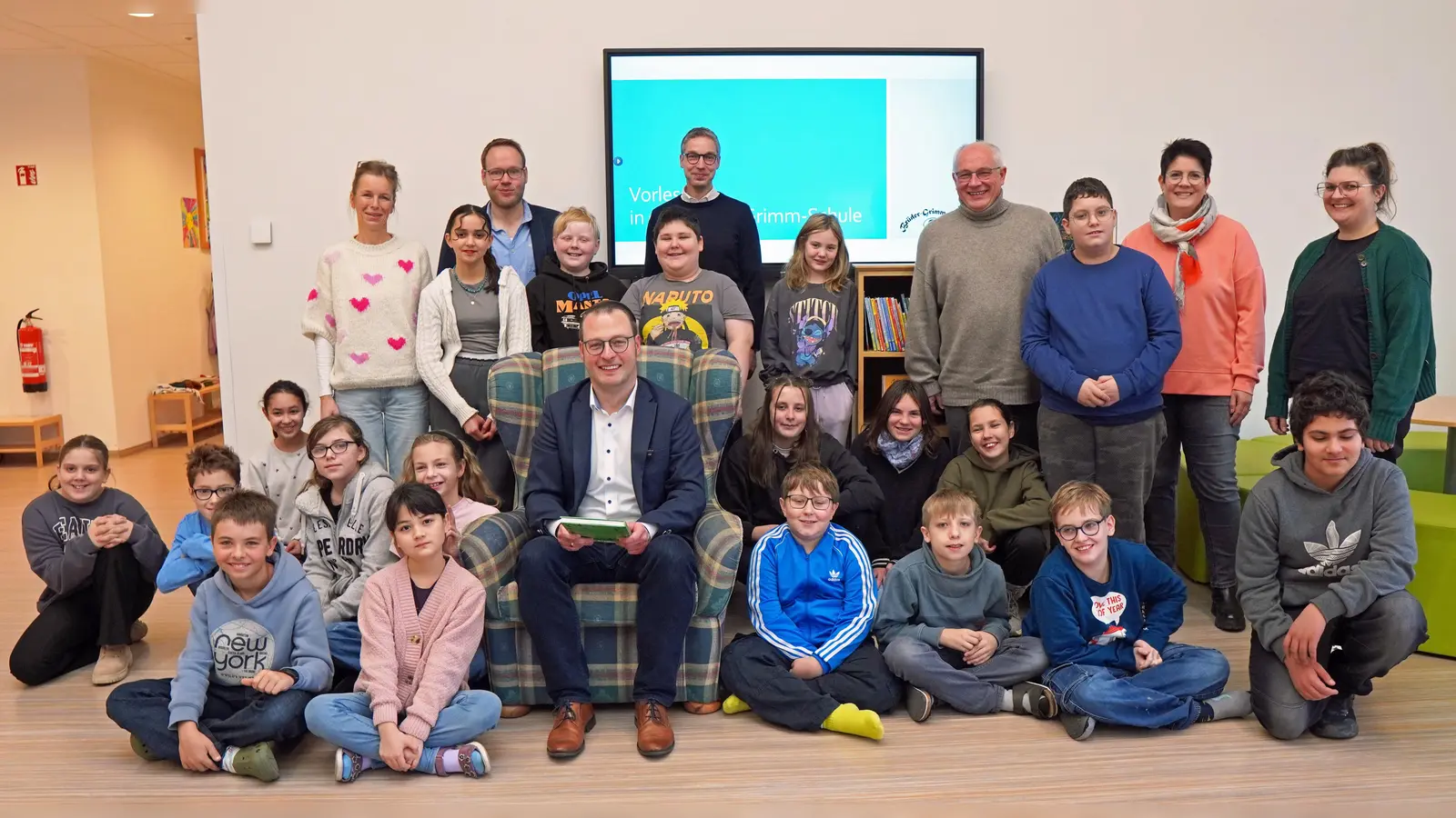 Bürgermeister Alexander Kleinschmidt (Mitte, sitzend) las den Schülerinnen und Schülern als Schirmherr der KulturKonferenz aus „Der Räuber Hotzenplotz“ vor. Organisiert wurde die gemeinsame Leseaktion durch (von links) Corinna Roland (Brüder Grimm Schule), Thomas Conze (Schulen der Brede), Manuel Eller (Brüder-Grimm-Schule), Gerhard Antoni (Berufskolleg Kreis Höxter) sowie Manuela Seeboth und Friederike Menne von der Adolph Kolping Förderschule. (Foto: Stadt Brakel)