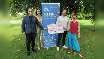 V.l.: Raphael Rosenstein (Vorsitzender Wirtschaftsjunioren PB+HX), Sommerfest-Organisatorin Jacqueline Voßmann und WJ-Mitglied Timm Westmark übergeben den symbolischen Spendenscheck in Höhe von 1.100 Euro an Emilia alias Sandra Bernhardt von den Paderborner Klinikclowns. (Foto: Wirtschaftsjunioren PB+HX / Julika Kleibohm)