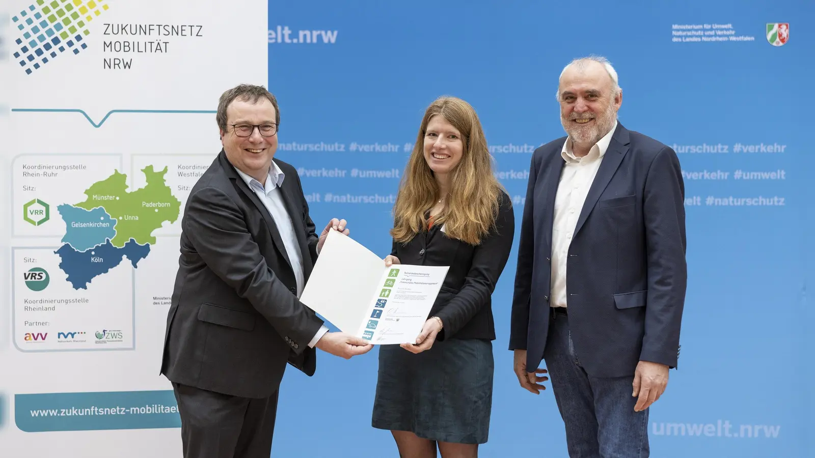 Höxter hat eine neue Mobilitätsmanagerin - Verkehrsminister Oliver Krischer (l.) und Theo Jansen, Geschäftsstellenleiter des Zukunftsnetz Mobilität NRW, übergeben Karolin Bludau nach erfolgreichem Abschluss eine Urkunde. (Foto: Ralph Sondermann)