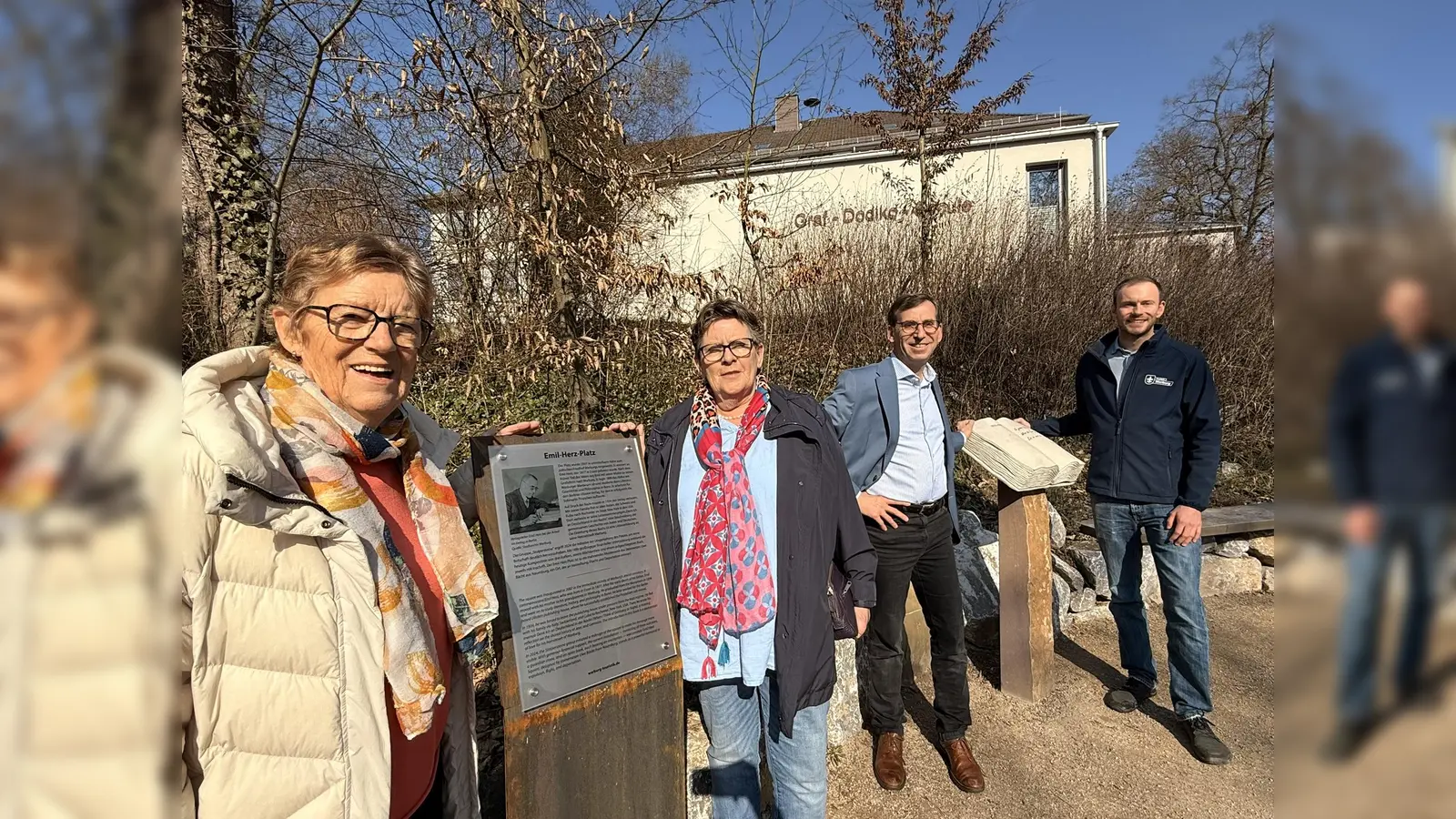 Eine neue Tafel informiert zukünftig auf Deutsch und Englisch über den in Warburg aufgewachsenen jüdischen Verleger Emil Herz. Die Initiatorinnen der Stolperstein-Gruppe Irmgard Heuel (v.l.) und Ruth Kröger-Bierhoff sowie Bürgermeister Tobias Scherf und Touristiker Lucas Lambracht freuen sich, dass der 2024 neu gestaltete Emil-Herz-Platz nun einen textlichen Bezug zu seinem Namensgeber hat. (Foto: Stadt Warburg)