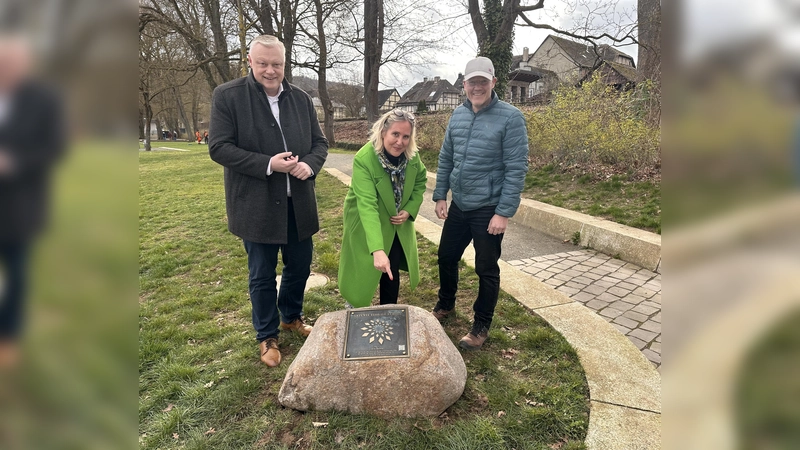 Bürgermeister Daniel Hartmann und Baudezernentin Julia Gogrewe präsentieren gemeinsam mit Johannes Pamme, Leiter der Stadtgärtnerei, den Findling mit der angebrachten Siegerplakette des Wettbewerbs „Entente Florale“ an der Weserpromenade in Höxter. (Foto: Stadt Höxter)