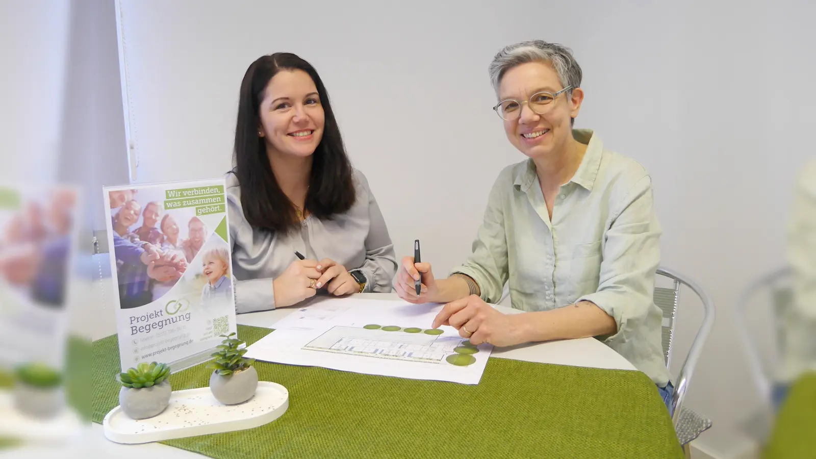 Sarah Austermühl (links) und Meike Becker besprechen mit einem Plan der neuen Kita in Beverungen Details der Innenraumgestaltung. (Foto: Schwannecke/Projekt Begegnung)