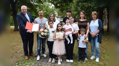 Freude über die Ehrenpatenschaft: Bürgermeister Daniel Hartmann, Abteilungsleiterin Lydia Drüke und die Familie Gossen feiern gemeinsam die besondere Auszeichnung durch Bundespräsident Frank-Walter Steinmeier. (h.v.l.) Bürgermeister Hartmann, Andre, Margarete, Michael und Olivia Gossen sowie Abteilungsleiterin Lydia Drüke. (v.v.l.) Daniel, Vitalina, Sofia-Viktoria, Juliana und Leonid Gossen. (Foto: Stadt Höxter)