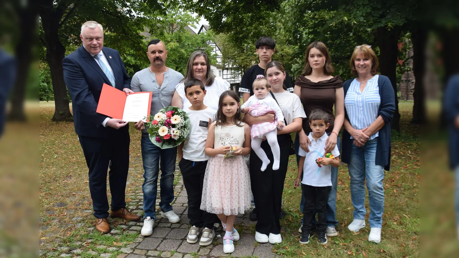 Freude über die Ehrenpatenschaft: Bürgermeister Daniel Hartmann, Abteilungsleiterin Lydia Drüke und die Familie Gossen feiern gemeinsam die besondere Auszeichnung durch Bundespräsident Frank-Walter Steinmeier. (h.v.l.) Bürgermeister Hartmann, Andre, Margarete, Michael und Olivia Gossen sowie Abteilungsleiterin Lydia Drüke. (v.v.l.) Daniel, Vitalina, Sofia-Viktoria, Juliana und Leonid Gossen. (Foto: Stadt Höxter)