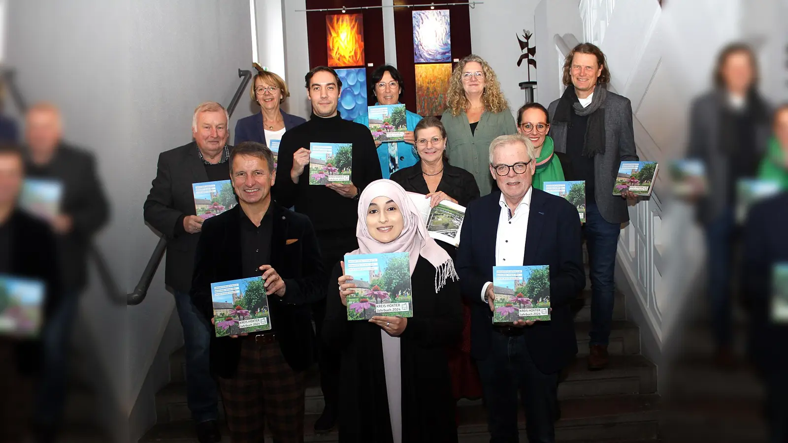 Pünktlich zur Vorweihnachtszeit präsentieren (1. Reihe von links) Landrat Michael Stickeln, Layla Youssef vom Kulturbüro des Kreises Höxter und Kreisdirektor Klaus Schumacher gemeinsam mit den Mitgliedern der Jahrbuchredaktion (hintere Reihen von links), Kreisheimat pfleger Hans-Werner Gorzolka, der Leiterin der Abteilung Schule und Kultur des Kreises Höxter, Gabriele Böker, Kreisarchivar Hendrik Köplin, Pressereferentin Silja Polzin, Dr. Claudia Konrad sowie Kristin Wiechers und Julia Siebeck vom Kulturbüro des Kreises Höxter und Verleger Jörg Mitzkat, das neue Jahrbuch des Kreises Höxter, das im Buchhandel erhältlich ist. (Foto: Kreis Höxter)
