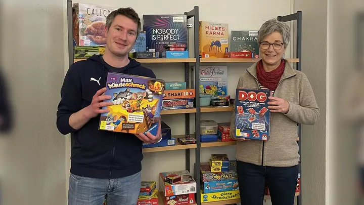 Büchereimitarbeiter Jörg Hoffmann und Andrea Tolle vor dem Spiele-Regal. (Foto: Stadt Holzminden)