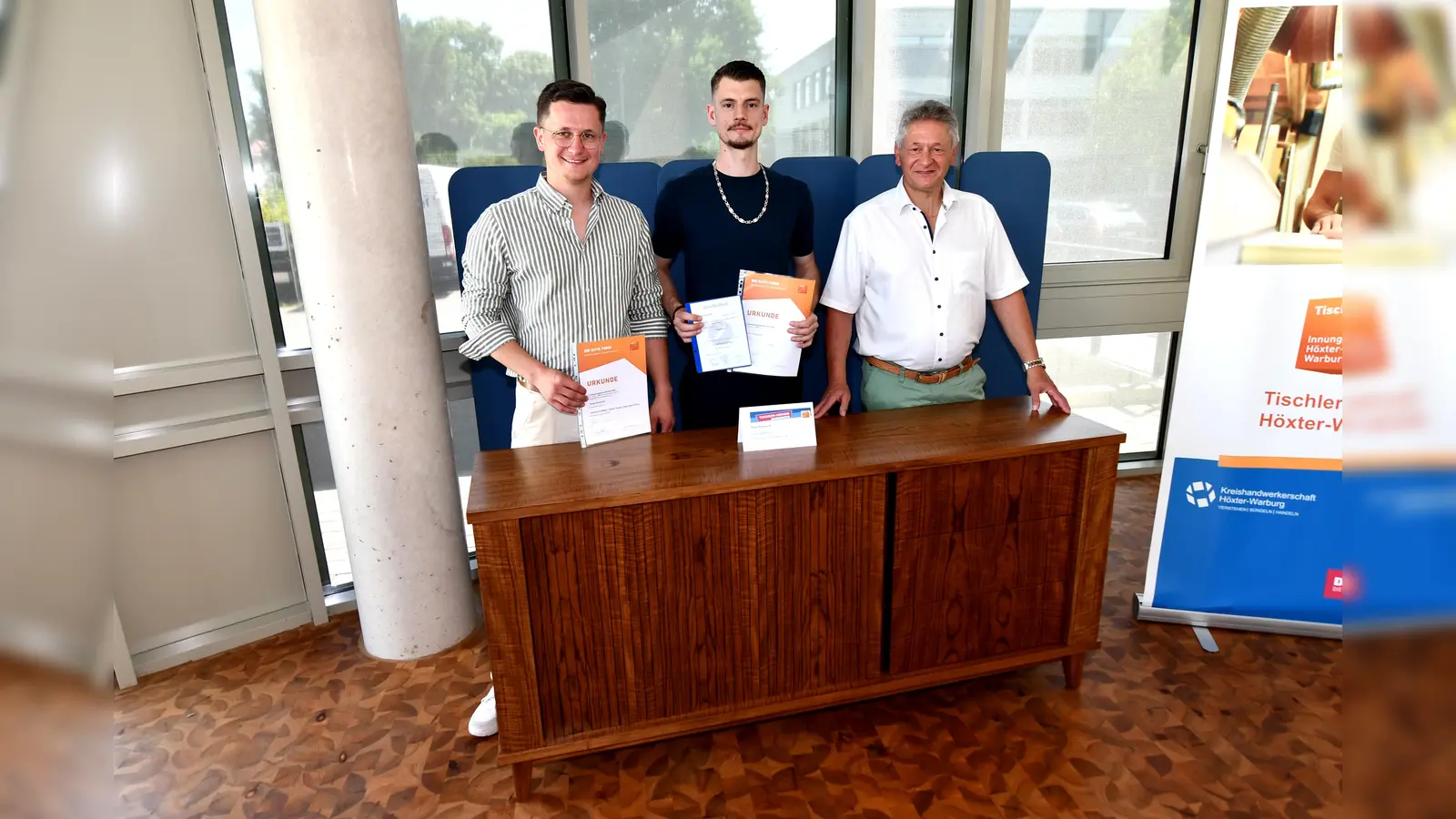 Die beiden Geschäftsführer des Familienbetriebs Heinemann Möbel-Objekt-Design GmbH, Lennart Heinemann (links) und Dirk Heinemann (rechts), gratulieren Renee Ritzenhoff aus Brakel zum 1. Platz. (Foto: Kreishandwerkerschaft Höxter-Warburg)