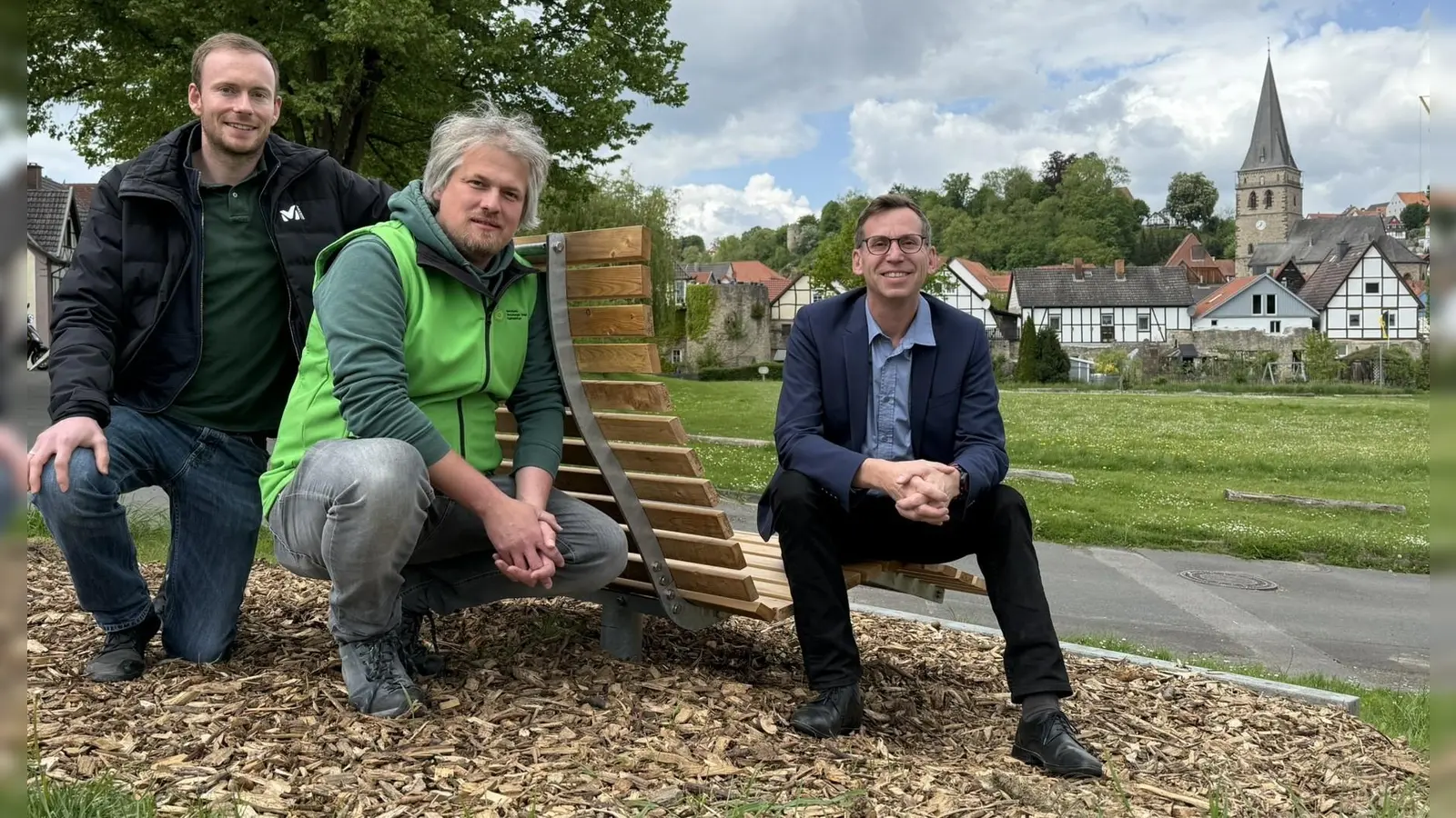 Mit Blick auf die Südansicht der Hansestadt Warburg: Touristiker Lucas Lambracht (v.l.), Henning Arnecke vom Naturpark Teutoburger Wald / Eggegebirge und Bürgermeister Tobias Scherf bei einer der beiden Panoramabänke auf dem Kälken.  (Foto: Stadt Warburg)