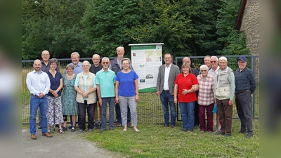 Ortsheimatpfleger und Initiator Reinhard Koch (links neben der Tafel), der Allgemeine Vertreter des Bürgermeisters, Alexander Kleinschmidt, (rechts neben der Tafel) und Wirtschaftsförderer David Prott (ganz links) freuen sich mit den Bewohnern aus Hainhausen über die Realisierung des Projektes. (Foto: Stadt Brakel)