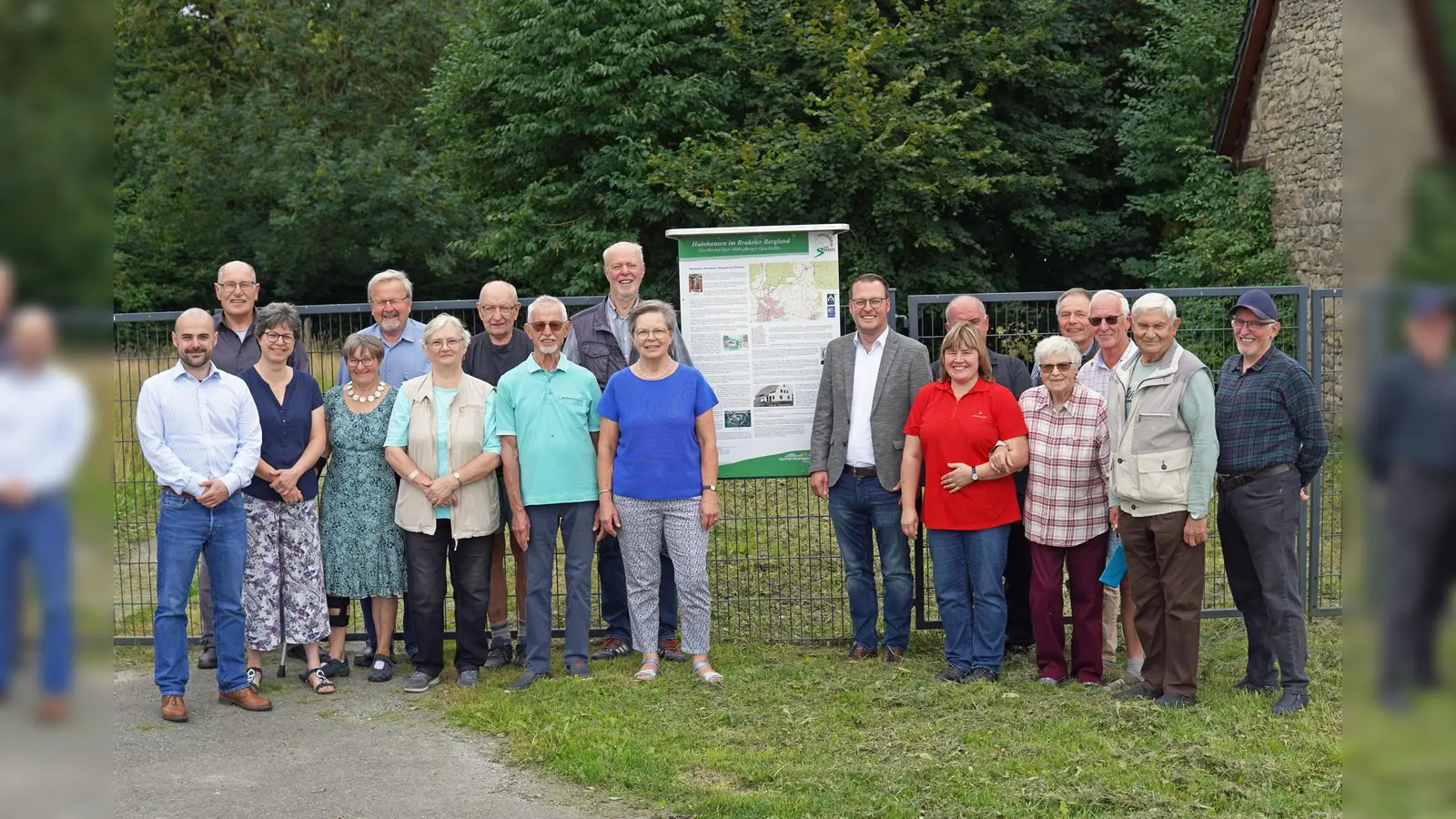 Ortsheimatpfleger und Initiator Reinhard Koch (links neben der Tafel), der Allgemeine Vertreter des Bürgermeisters, Alexander Kleinschmidt, (rechts neben der Tafel) und Wirtschaftsförderer David Prott (ganz links) freuen sich mit den Bewohnern aus Hainhausen über die Realisierung des Projektes. (Foto: Stadt Brakel)