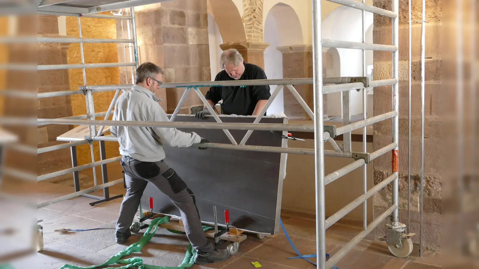 Mit größter Sorgfalt bereiten Restaurator Matthias Rüenauver (rechts) und sein Mitarbeiter Olav Renger im Johanneschor den Hub der berühmten Inschriftentafel vor. (Foto: Kirchengemeinde Corvey)