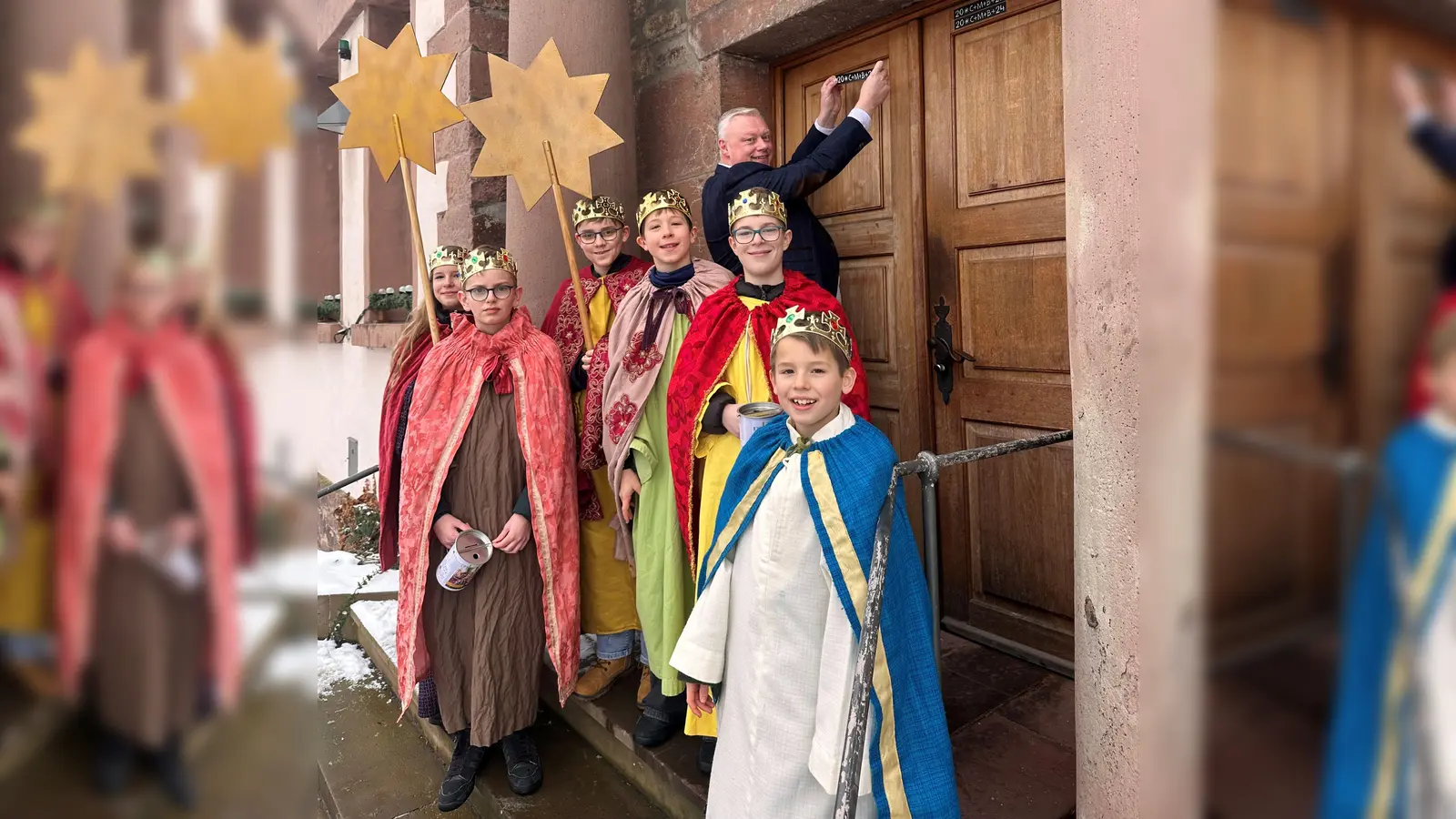 Bürgermeister Hartmann freut sich über den Besuch der Sternsinger; v.l. Marlene, Henri, Philipp, Justus, Benjamin und Theo. Der erste Segensaufkleber wurde an der Tür des Stadthauses angebracht. (Foto: Stadt Höxter)