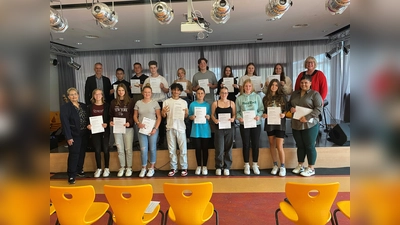 Die Schülerinnen und Schüler sind sichtlich stolz auf ihre Zertifikate als Fahrzeugbegleiterinnen und -begleiter: (hinten von links) Schulleiter Driton Mazrekaj, Aayan Malik, Kevin Kollmeyer, Maurice Kelm, Stacey Gabler, Simeon Bergau, Lena Alberding, Mia Lange, Lenja Koch, Erste Kreisbeigeordnete Silke Engler; (vorne von links) Ausbilderin Birgit Schaumburg, Mila Patermann, Lenja Schüttemeyer, Hanne Rudolff, Faizullah Gulzari, Sofia Gobrecht, Anna Schröder, Leni Otto, Anika Schäfer und Trainerin Gentiana Syla.  (Foto: Landkreis Kassel)