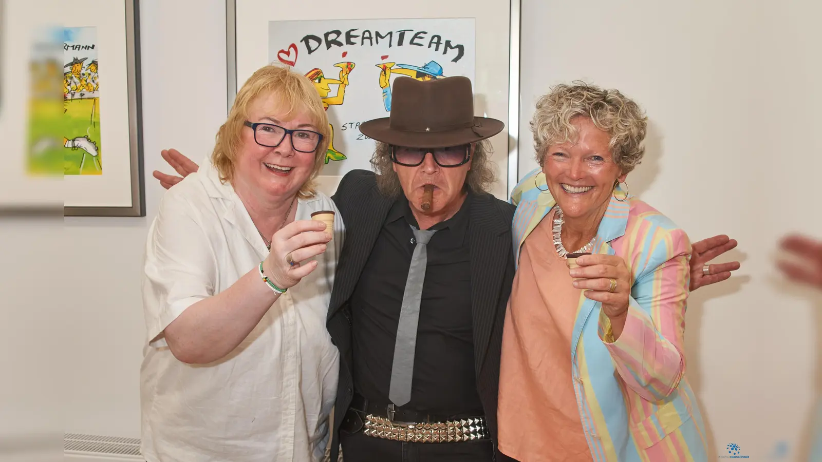 „Stößchen“ mit Eierlikörchen: Corinna Leimbach (l.) und Sabine Ganter-Shaw konnten zur Eröffnung der Ausstellung mit Bildern von Udo Lindenberg zahlreiche Besucher in ihren Räumen am Marktplatz begrüssen. Für echtes „Udo-Feeling“ sorgte dabei Lindenberg-Double Karsten Bald. (Foto: Stefan Bönning)
