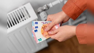 heating, energy crisis and consumption concept - close up of hands with money on radiator at home (Foto: Verbraucherzentrale NRW/adpic)