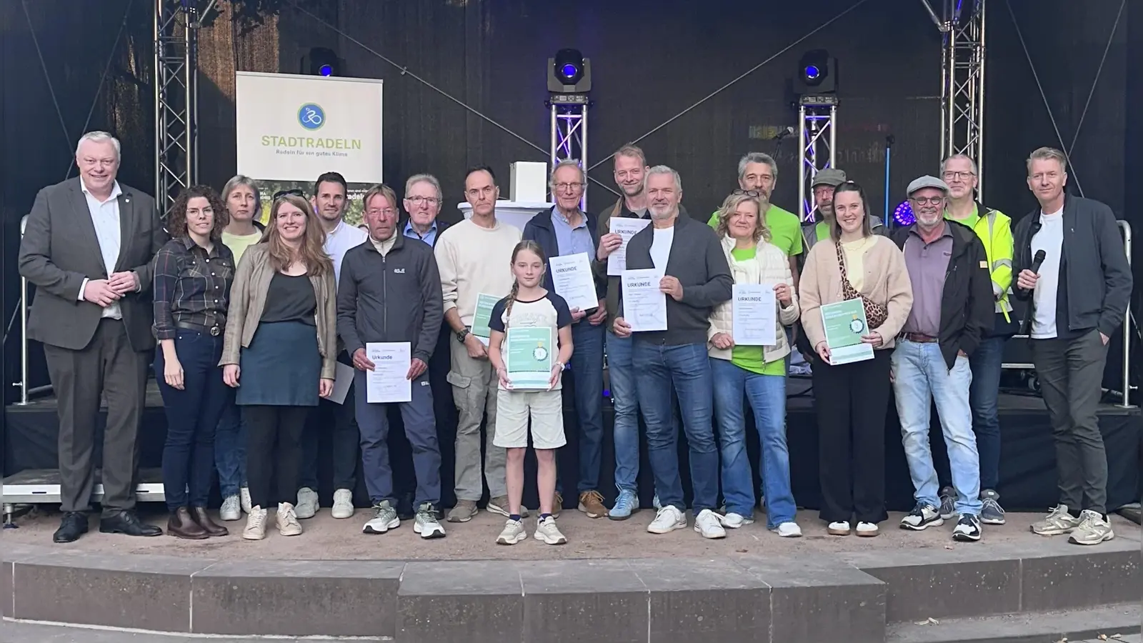 Die ausgezeichneten Teilnehmerinnen und Teilnehmer des Stadtradeln 2026 gemeinsam mit Bürgermeister Daniel Hartmann (links) und Moderator Markus Finger (rechts) bei der Preisverleihung auf dem Höxteraner Marktplatz. (Foto: Stadt Höxter)
