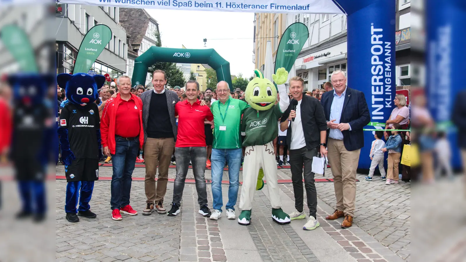 Rekord- Resonanz beim 11. Firmenlauf Höxter (v.l.): Mehr als 1.250 Aktive aus mehr als 120 Firmen wurden von SCP-Maskottchen ‚Holli‘; Achim Frohß (Vorstandsmitglied Sparkasse Paderborn-Detmold-Höxter), Jens Klingemann (Geschäftsführer Sport- und Modehaus Klingemann), Jörg Albers (Unternehmenskundenbetreuer Sparkasse Paderborn-Detmold-Höxter), Thomas Pottmeier (Teamleiter Vertrieb AOK NordWest), AOK-Maskottchen ‚Jolinchen‘, Moderator Markus Finger und Daniel Hartmann (Bürgermeister Stadt Höxter) auf die Strecke geschickt. (Foto: AOK/hfr.)