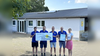 Der Vereinsvorstand (v. l.) Patrik Scholz (2. Schriftführer), Christian Thöne (2. Kassierer), Matthias Göbel (2. Vorsitzender) und Holger Dierkes (1. Vorsitzender) bedankte sich bei Julia Franzmann (BeSte Stadtwerke) für die Unterstützung und präsentierte das Balkonkraftwerk auf dem Dach des Vereinsheims (Hintergrund). (Foto: BeSte Stadtwerke GmbH)