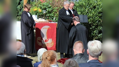 Superintendent Volker Neuhoff (Mitte) führt Frank Schubert (knieend) in seinen Dienst im Interprofessionellen Pastoralteam der Evangelischen Kirchengemeinde Altkreis Warburg ein. An der Einführung wirkten mit Diplom-Theologin und Gemeindepädagogin Frederike Wieneke (l.) und Synodalassessor Pfarrer Gunnar Wirth (r.). (Foto: EKP/Oliver Claes)
