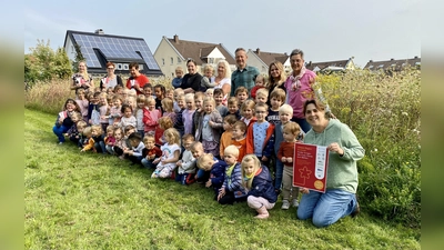 Große Freude bei den Kindern und Erzieherinnen in der Blühwiese vor der Kita „Zum verklären Christus“ in Bad Driburg. Mit auf dem Foto sind Maria Kemker (Westenergie-Kommunalmanagerin; hinten links), Andrea Koch (stellvertretende Leiterin der Kita; vorne rechts), Diego Krämer (Untere Naturschutzbehörde des Kreises Höxter; Dritter von rechts hinten), Martina Krog (Klimaschutzbeauftrage des Kreises Höxter; rechts hinten). (Foto: Kreis Höxter)