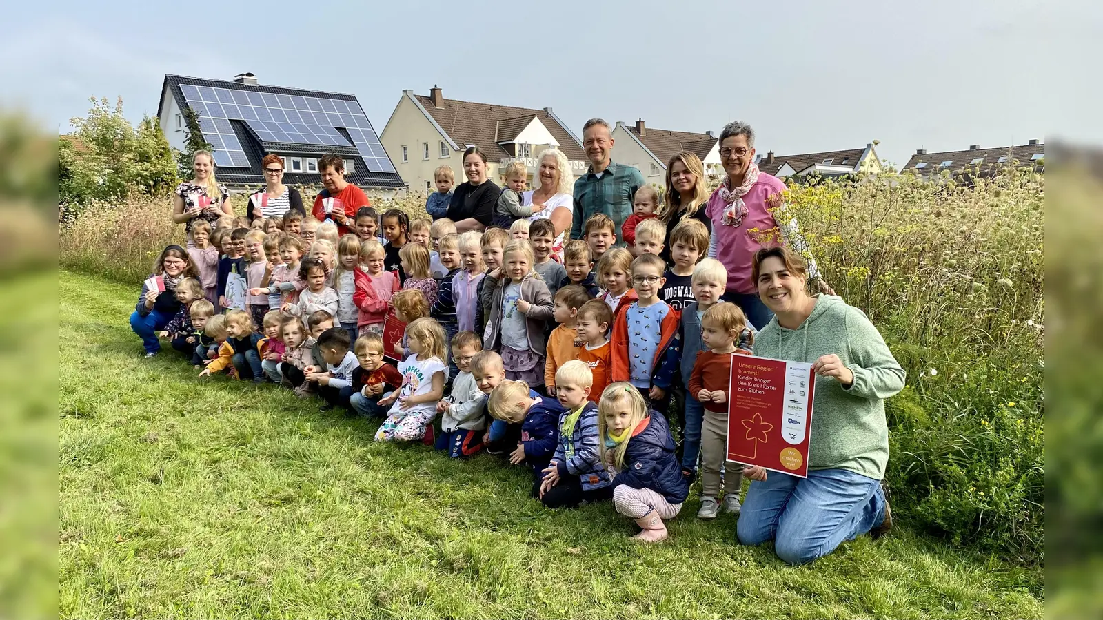 Große Freude bei den Kindern und Erzieherinnen in der Blühwiese vor der Kita „Zum verklären Christus“ in Bad Driburg. Mit auf dem Foto sind Maria Kemker (Westenergie-Kommunalmanagerin; hinten links), Andrea Koch (stellvertretende Leiterin der Kita; vorne rechts), Diego Krämer (Untere Naturschutzbehörde des Kreises Höxter; Dritter von rechts hinten), Martina Krog (Klimaschutzbeauftrage des Kreises Höxter; rechts hinten). (Foto: Kreis Höxter)