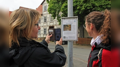 Sonja Frank (links) und Diana Schlundt probieren am Schild für den Posthof in der Kasseler (früher Holländischen) Straße den QR-Code für das Abspielen der Erläuterungen auf Westuffler Platt aus. (Foto: Brunhilde Berndt)