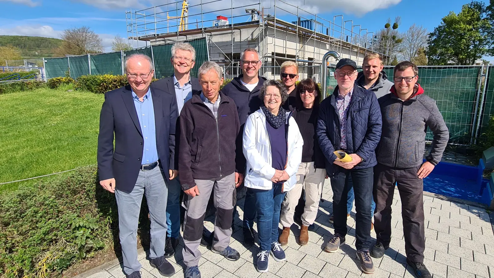 Freuen sich vor dem im Bau befindlichen Umkleidegebäude auf die neue Badesaison: (v.l.) Bürgermeister Hubertus Grimm, Thomas Rochell, Kurt Wiemers, Heiner Hake, Brigitte Preuß, Alexander Klaus, Dagmar Roscher, Uwe Lippenmeyer, Florian Seela und Sebastian Mann. (Foto: Peter Vössing)