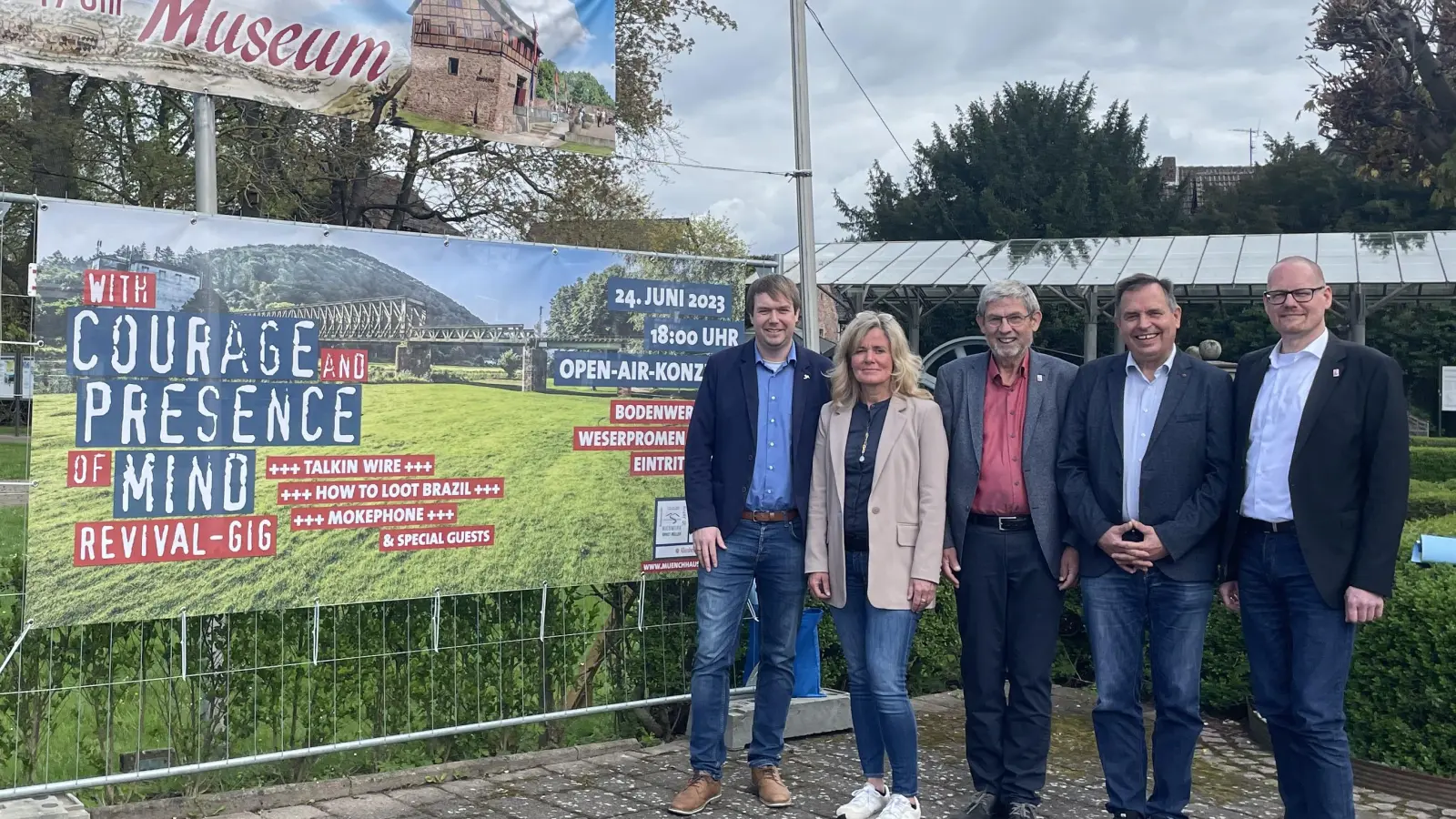 Sebastian Rode Samtgemeindebürgermeister; Heike Mangold-Lott, Samtgemeinde Bodenwerder-Polle; Friedrich-Wilhelm Dornette, Bürgermeister der Stadt Bodenwerder; Eckhard Henke, Geschäftsführer des Kieswerks Ernst Müller GmbH &amp; Co. KG und Michael Helmig, Fachbereichsleiter der Samtgemeinde Bodenwerder-Polle vor dem Banner des Open-Air-Konzertes. (Foto: Samtgemeinde Bodenwerder-Polle)