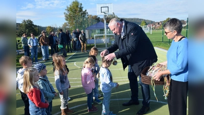 Bürgermeister Daniel Hartmann überreicht den Kindern als Anerkennung für ihre Teilnahme an der Eröffnungsfeier Medaillen. Die Freude über die Auszeichnung und den neuen Platz ist groß. (Foto: Stadt Höxter)