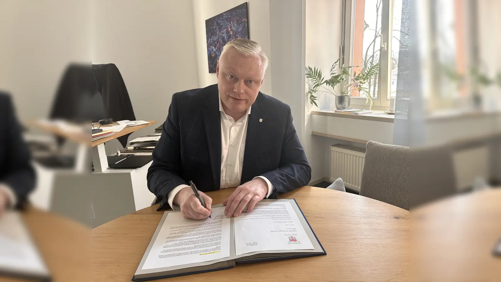 Bürgermeister Daniel Hartmann setzt seine Unterschrift unter den Widerspruch gegen den Ratsbeschluss zum Umbau des Postgebäudes „Uferstraße 2“. Mit seiner Unterschrift macht er deutlich: Die Zukunft des MVZ und des ehemaligen Postgebäudes soll auf fundierter fachlicher Grundlage entschieden werden. (Foto: Stadt Höxter)