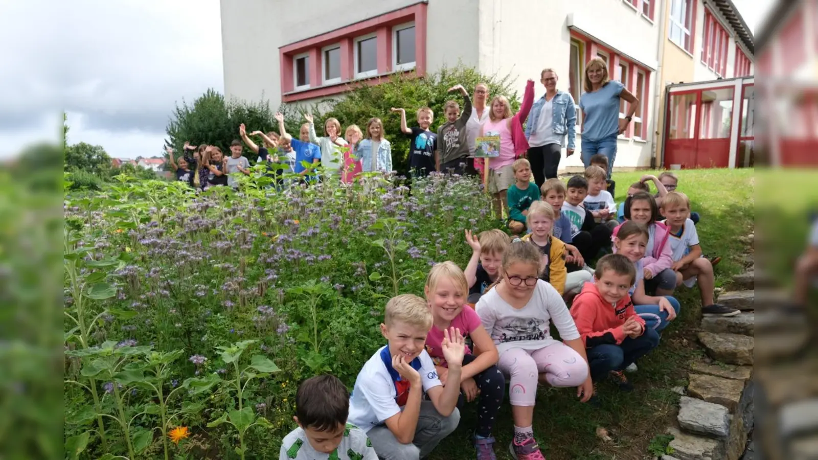 Die Flexklassen der Grundschule Hombressen freuen sich gemeinsam mit Lehrerin Silvia Zackenfels, Biodiverstitätsbeauftragte Dr. Julia Rosa-Schleich und Lehrerin Kerstin Homburg-Broll (hinten rechts) über die neue Blühfläche an der Schule.  (Foto: Landkreis Kassel)