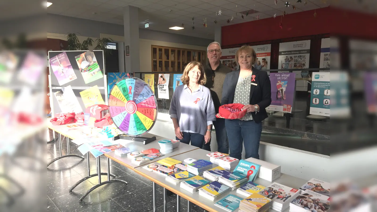Mit einem Info-Stand möchte die Abteilung Gesundheitsvorsorge des Kreises Höxter zum Welt-Aids-Tag am Berufskolleg Kreis Höxter in Brakel Fragen rund um HIV und andere sexuell übertragbaren Erkrankungen beantworten. Die Beratung übernehmen Susanne Heinemeyer (r.), Martina Delker-Brenneker und Boris Gemmeke vom Kreis Höxter. (Foto: Kreis Höxter)