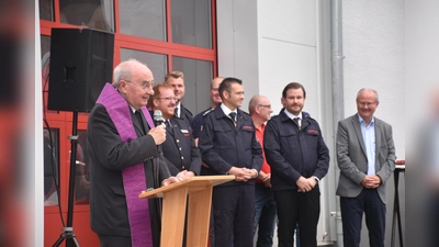 Mit Andacht und Weihwasser gab Pastor Günter Weige dem neuen Fahrzeug und dem Anbau den Segen und bat um göttlichen Schutz für die ehrenamtlichen Feuerwehrleute. (Im Hintergrund v. l.) Kreisbrandmeister Stefan Nostitz, der Leiter der FFW Beverungen Sebastian Even, Löschgruppenführer Nils Hanewinkel und Bürgermeister Hubertus Grimm. (Foto: Barbara Siebrecht)